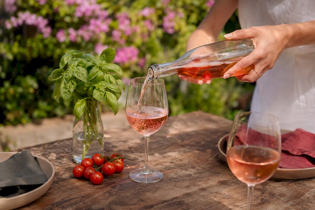 Glass of rosé wine being poured outdoors