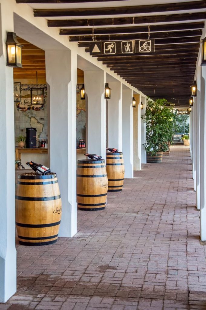 A picturesque winery entrance with lanterns and wooden barrels lining the cobblestone path.