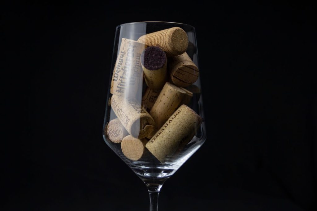 Elegant close-up of various wine corks in a wine glass against a dark background, highlighting texture and detail.
